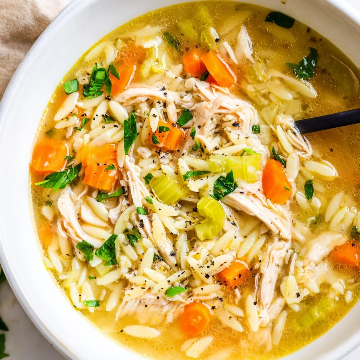 A comforting pot of Lemon Pepper Chicken Orzo Soup simmers with carrots and celery, ready to be ladled into rustic bowls.  
