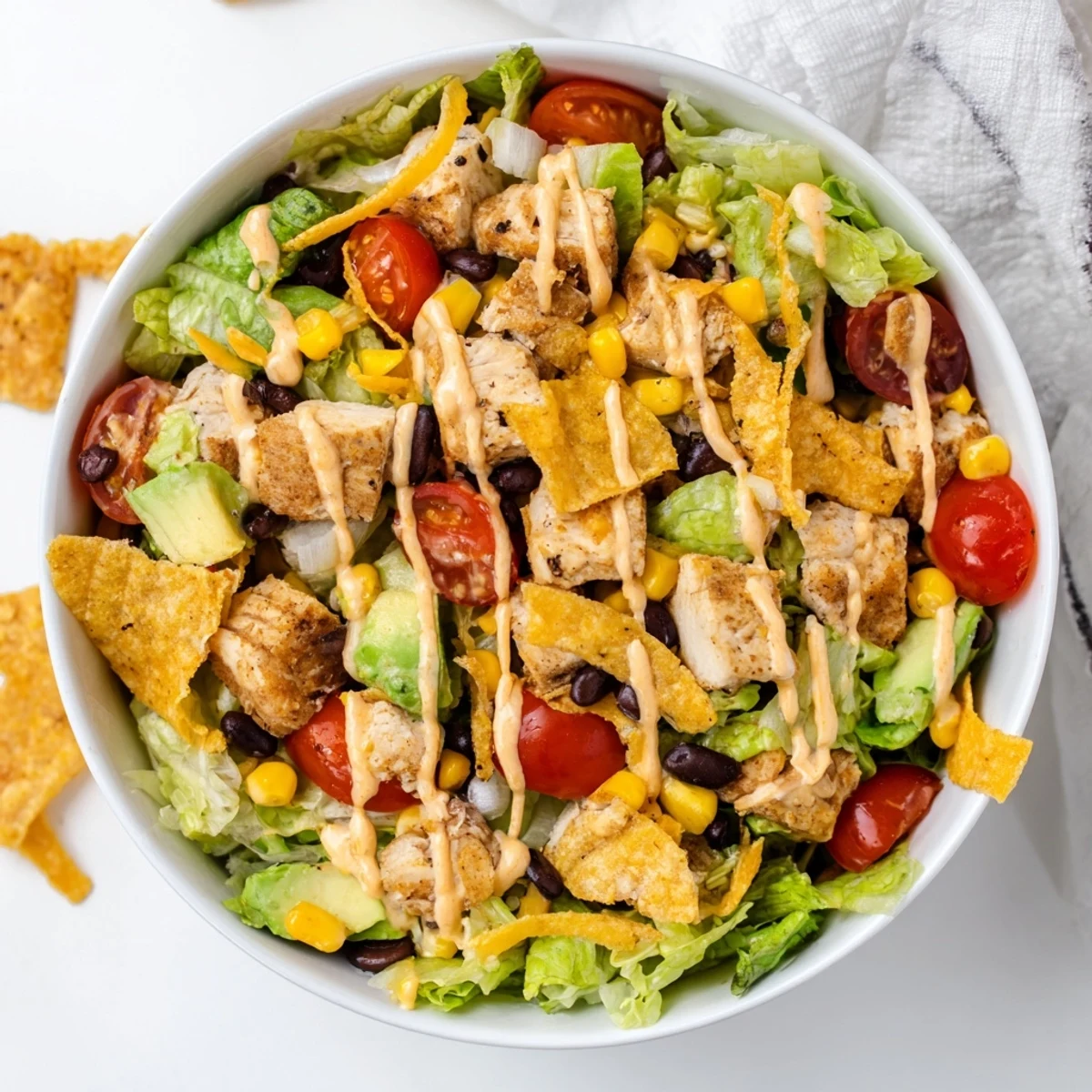 A vibrant bowl of Chicken Taco Chopped Salad topped with creamy salsa ranch and crushed tortilla chips.  