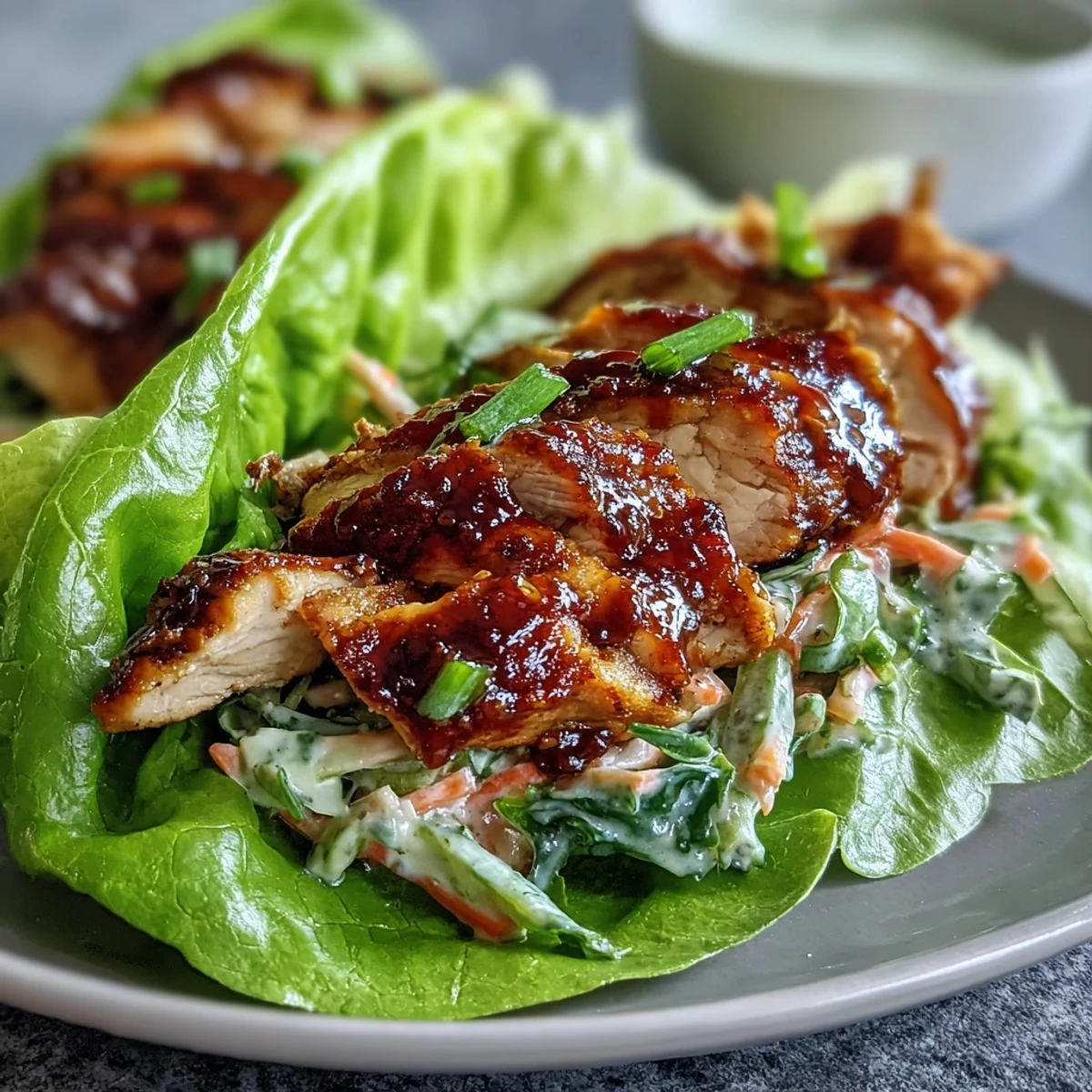 High-protein BBQ chicken lettuce wraps with slaw, featuring tender chicken in smoky sauce wrapped in crisp lettuce with crunchy cabbage slaw.
