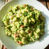 Freshly made Edamame Guacamole, speckled with cilantro, served in a wooden bowl for dipping.