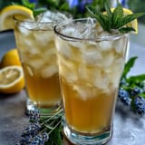 A tall glass of lavender lemonade infused with fresh mint, served over ice for a cool, aromatic beverage.