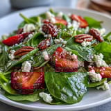 Spring Strawberry Spinach Salad with goat cheese, strawberries, and candied pecans on a white plate. A light, refreshing side dish perfect for spring and Easter gatherings.
