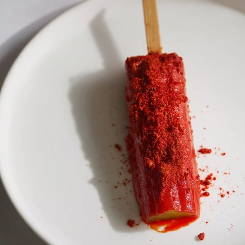 Bright red Chamoy-Tajín pickle sticks, the perfect Mexican-inspired snack, coated in zesty seasoning.