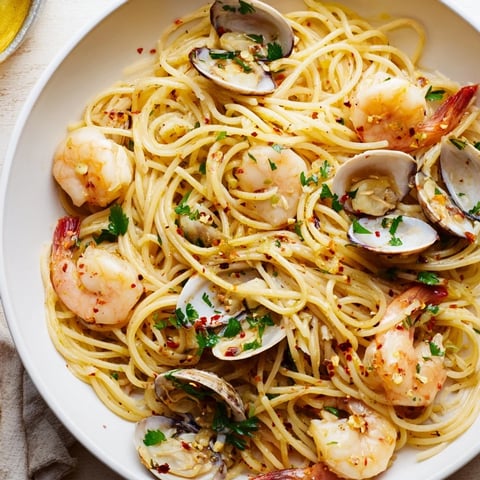Steaming Seafood Pasta Aglio e Olio with plump shrimp and clams, ready to serve with fresh parsley.