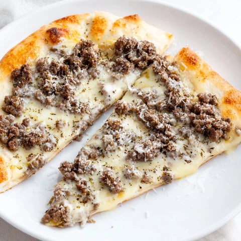 Ground Beef Alfredo Pizza features a golden crust, creamy sauce, and bubbling mozzarella, ready to serve.