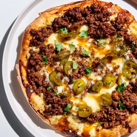 Fresh-baked spicy ground beef pizza slices topped with hot honey and jalapeños, ready to serve and devour.