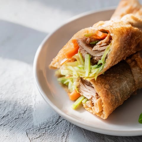Freshly pan-fried Garlicky Pulled Chicken Wraps stacked on a platter, revealing steaming, savory garlic-butter chicken filling inside rice paper.  