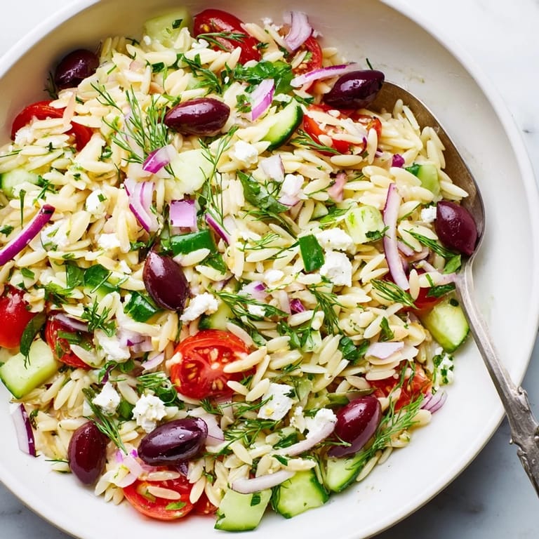 Bright and refreshing Greek Orzo Salad served in a white bowl, garnished with fresh parsley and Kalamata olives, perfect for a sunny picnic side dish.