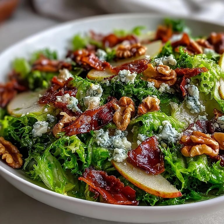 An overhead shot of Frisée, Pear, Blue Cheese, and Crispy Prosciutto Salad, with crisp prosciutto pieces, pear slices, and a drizzle of tangy vinaigrette over greens.