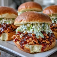 Juicy pulled BBQ chicken smothered in smoky sauce, piled high on toasted brioche buns for a hearty, flavorful sandwich.